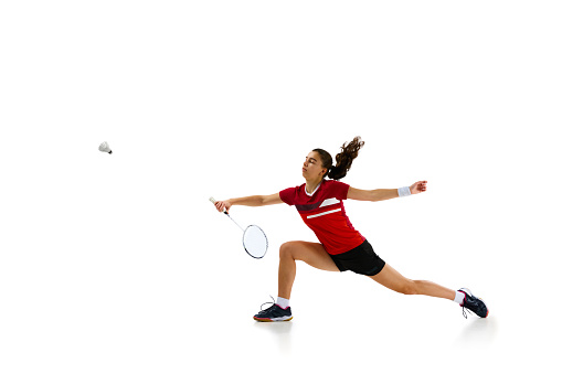 Athleticism and determination. professional female badminton player training in motion against white studio background. Concept of sport, active lifestyle, strength and power, action. Copy space.