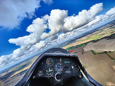 Glider cockpit in flight. Blue sky, clouds and fields seen from a sailplane