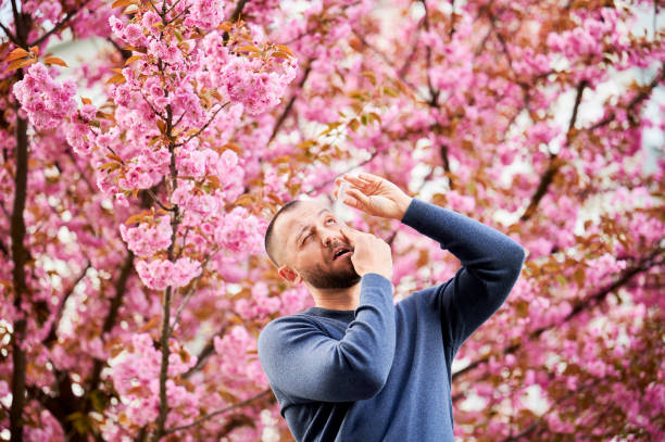 istock Man allergic using medical eye drop, suffering from seasonal allergy at spring in blossoming garden 1870047887