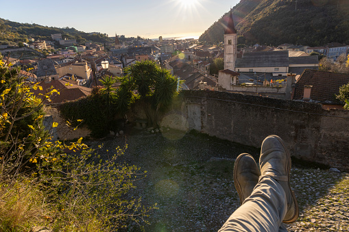 POV past legs to old village and church tower below