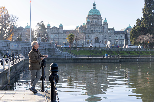 Mature man explores Victoria waterfront near BC Legislative buildings