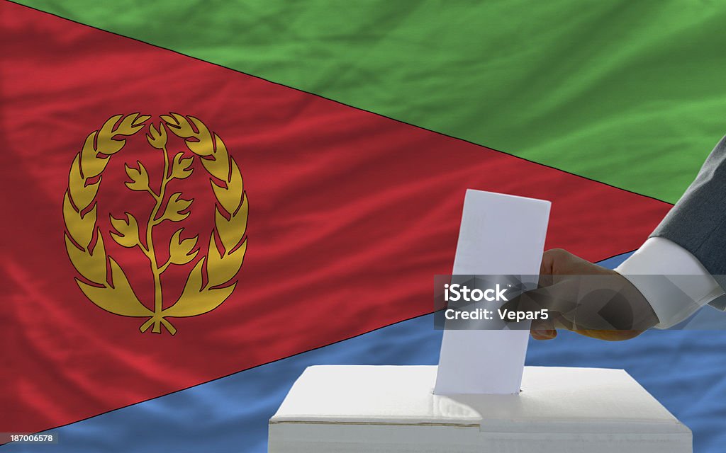 Uomo di voto sulle elezioni in davanti bandiera nazionale dell'eritrea - Foto stock royalty-free di Adulto