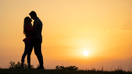 A romantic couple in love holding hands in the sunset