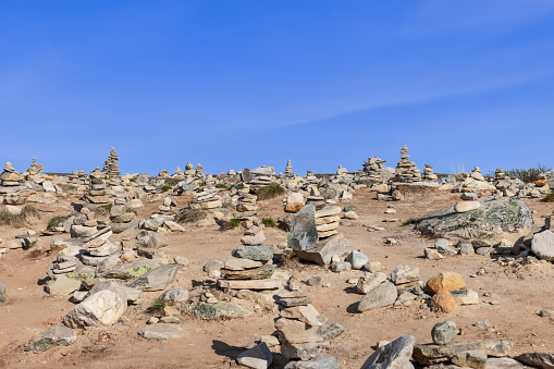 Stone pyramids (Cairn) meticulously assembled by visitors near the Arctic Circle Center in Rana, Nordland, Norway, stand under a clear blue summer sky