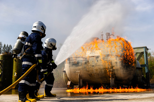 Firefighters safety using twirl water fog type fire extinguisher to fighting with fire from oil