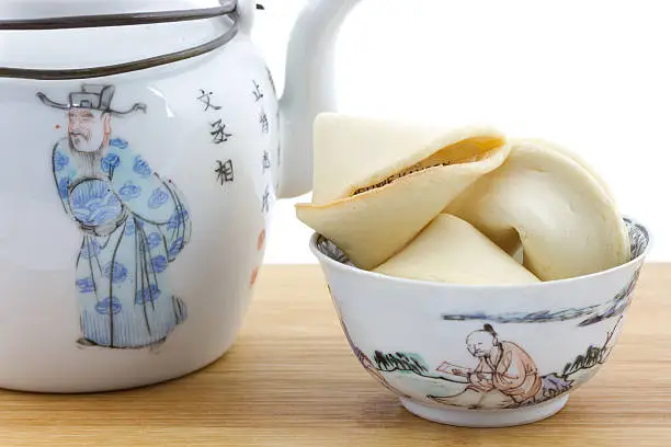 Chinese bowl and teapot with fortune cookie isolated on white