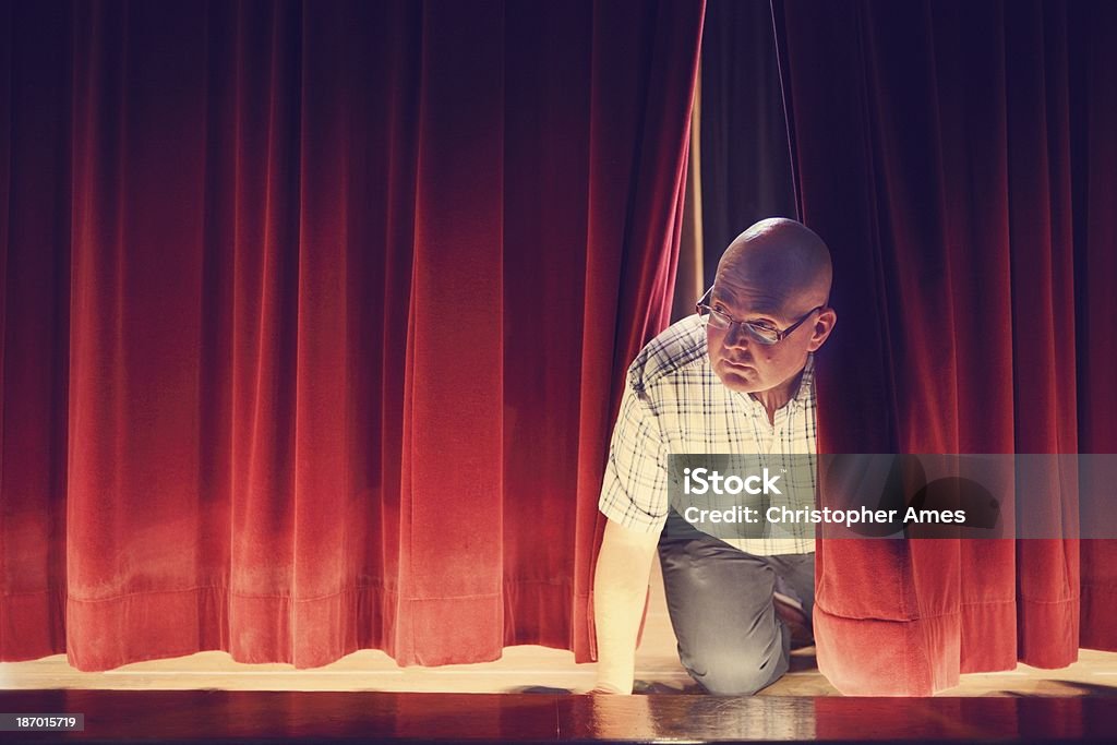 Uomo Sbirciare attraverso tende di palco rosso - Foto stock royalty-free di Recita della scuola