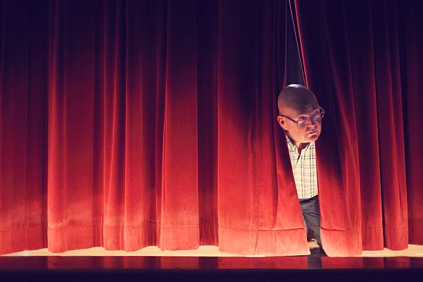 istock Man Peeking Through Red Stage Curtains 187015865
