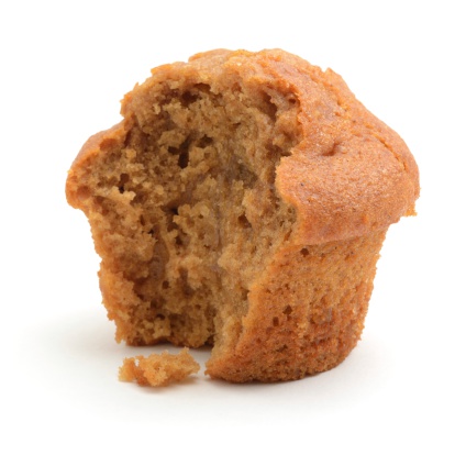 A half eaten ginger muffin isolated on a white background.