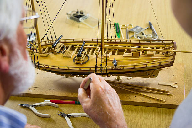 istock Boy Watches A Model Ship Builder Work In Classroom 187016518