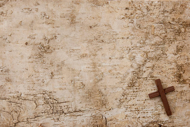 istock A small, dark wooden cross rests on flat tree bark 187016612