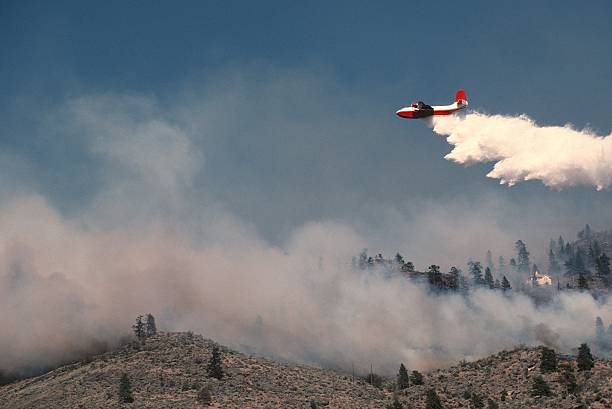 Air tanker spraying water on hillside fire. stock photo