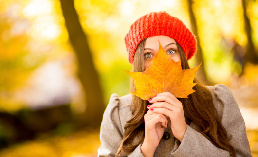 Portrait Of Young Woman Holding Maple Leaf In Front Of Face