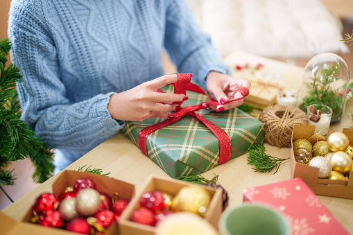 Woman in knitted sweater wrapping christmas presentsÂ with eco paper girl packing christmas gifts Xmas holiday concept.