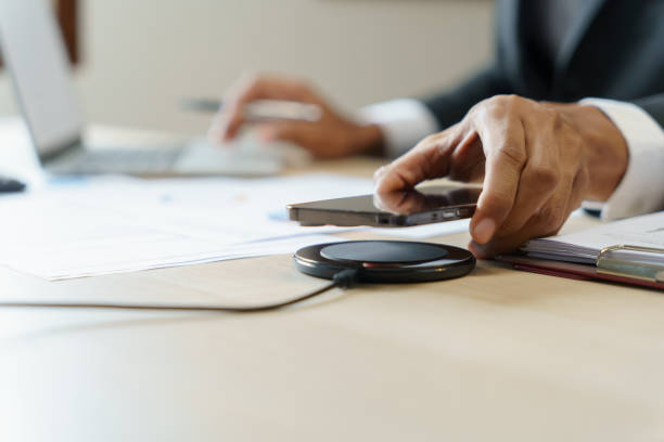 istock Charging mobile phone battery with wireless charging device in the table. Smartphone charging on a charging pad. Mobile phone near wireless charger Modern lifestyle technology concept 1870172487