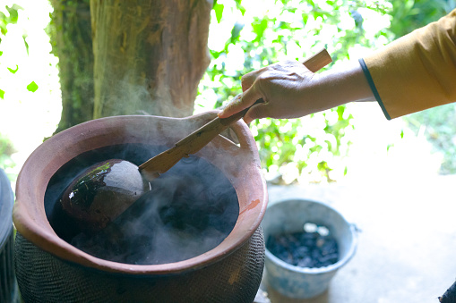 Thai woman is stirring  and boiling  thai herbal health water for foot bathing  into cauldron on fireplace in Chianfg Rai province