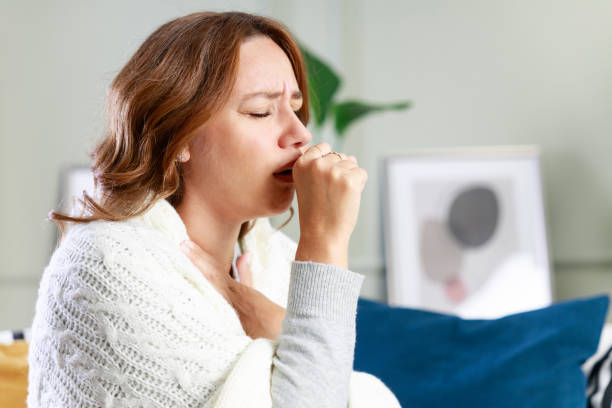 istock Sick woman sitting on couch and coughing while suffering from sore throat 1870207478