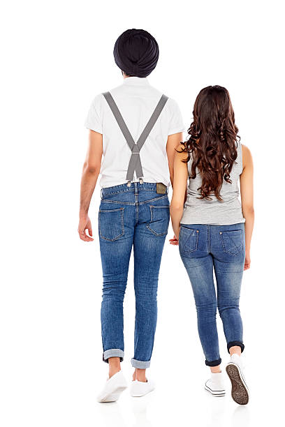 Rear view of young couple walking together on white background