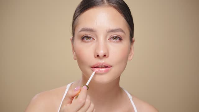 Beauty brunette woman applying lip gloss