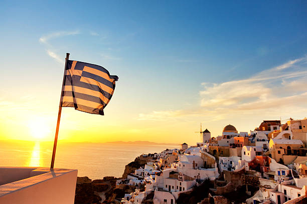 Greek flag waving at sunset in Oia, Santorini, Greece