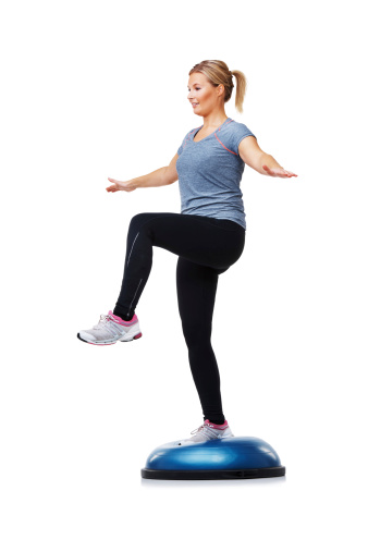 A young woman standing on a bosu-ball while working out