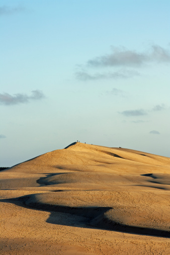 On the top of Europe's highest dune, the dune of Pyla, at the french atlantic coast near the town Arcachon. South west france, gulf of Biscaya (Cote d'argent). Warm light of the sunset. View from the northern end of the dune onto the southern top. Some people (not identifiable), far away, on the top of the dune.