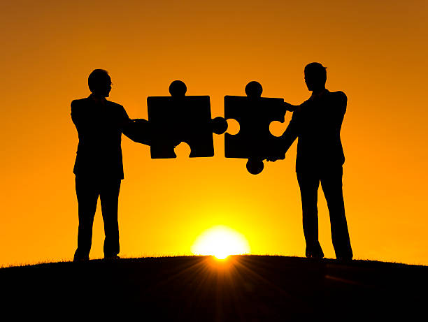 istock Silhouettes of two men, each holding a puzzle piece 187028001