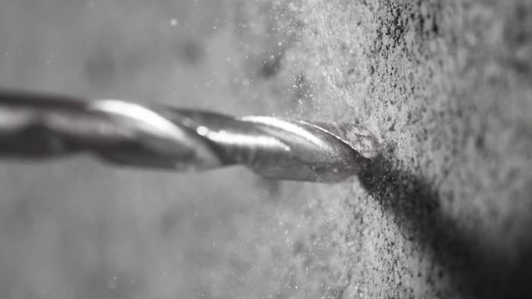 Super slow motion of detail of a drill bit drilling into concrete.