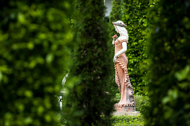 Female statue made from mortar in the summer garden with copy space. Decorative gardens.