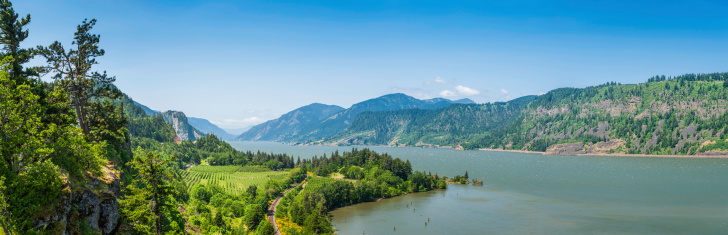 Sweeping panoramic vista over the farms and forests, dramatic rocky bluffs and rail tracks of the Columbia River Gorge, the picturesque National Scenic Area in the Cascade mountains of Oregon and Washington State, USA. ProPhoto RGB profile for maximum color fidelity and gamut.