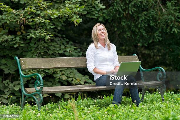 Rir Jovem Mulher Com Laptop No Banco De Parque - Fotografias de stock e mais imagens de Ao Ar Livre - Ao Ar Livre, Contente, Mulheres