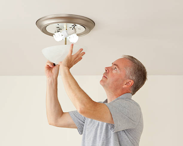 Changing Light Bulbs Man changing bulbs in a ceiling light. light fixture stock pictures, royalty-free photos & images
