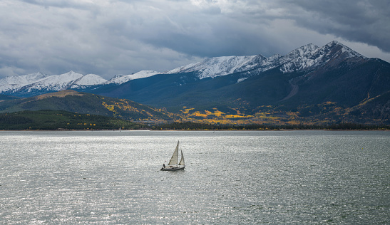 Dillon, Colorado, USA - October 1, 2022: A small boat sailing across Dillon Reservoir on a stormy Autumn day.
