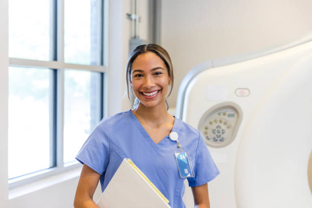 Cheerful nurse in front of CT scan machine