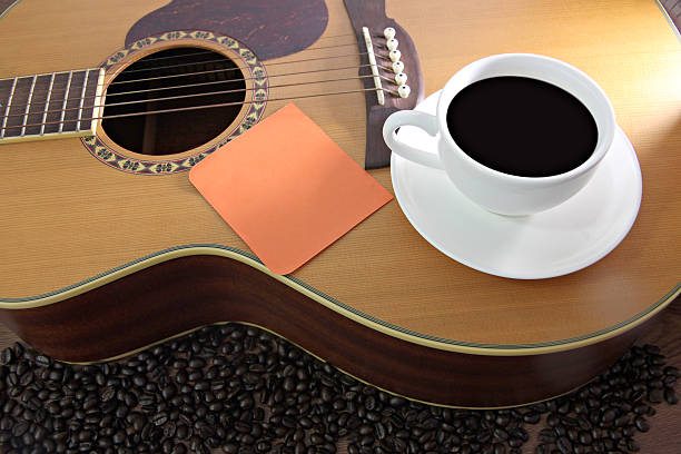 istock White coffee cup and Notebook paper orange resting on guitar. 187036809