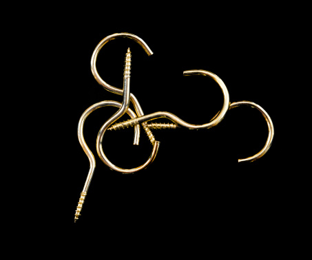 Brass coloured hooks isolated against a black background.