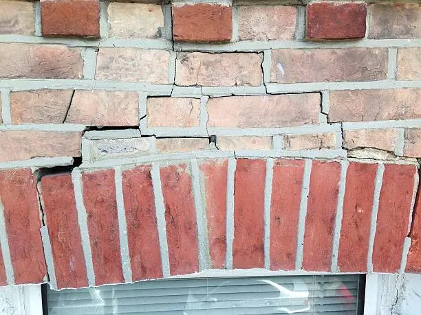 Structural brick arch above a window in a Victorian house. The structure is collapsing and has cracked.