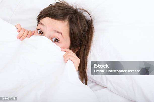 Young Girl Sentar En Su Cama Asustada Foto de stock y más banco de imágenes de 6-7 años - 6-7 años, Acostado, Acostado de espalda