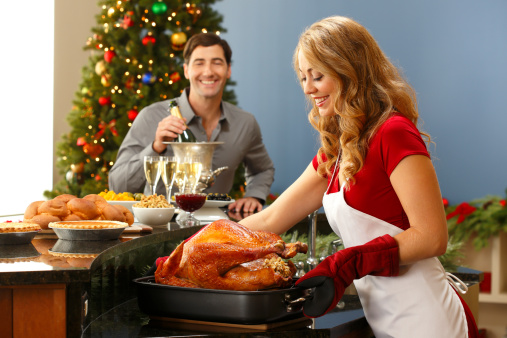 A man happily looking at the Christmas turkey his wife has just pulled out of the oven.
