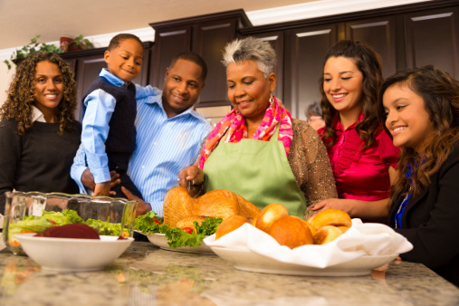 Family and neighbors gather together in senior woman's home to prepare Thanksgiving dinner.