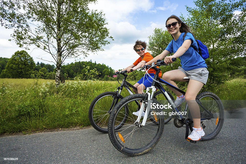 Miejski biking- dziewczynka i chłopiec konna rowery w mieście park - Zbiór zdjęć royalty-free (Bicykl)