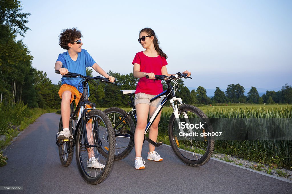 Miejski biking- dziewczynka i chłopiec konna rowery w mieście park - Zbiór zdjęć royalty-free (14-15 lat)