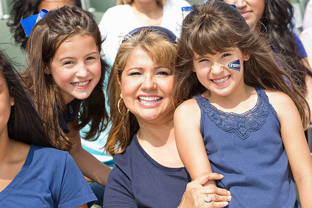 maman assister à un événement sportif au stade avec deux jeunes filles - sport parent bleachers family photos et images de collection