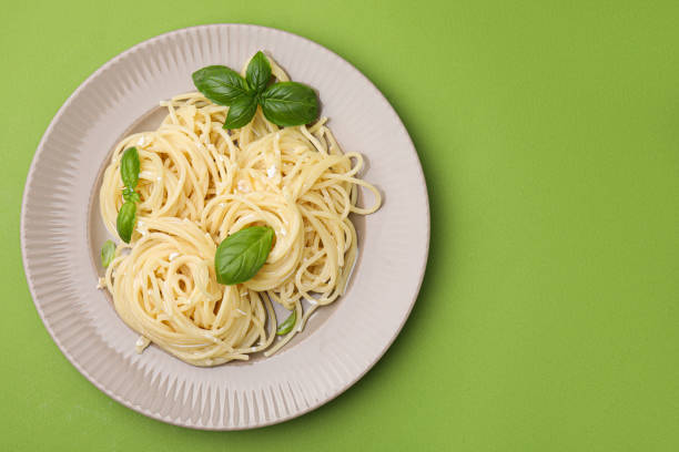 istock Delicious pasta with brie cheese and basil leaves on light green background, top view. Space for text 1870400421
