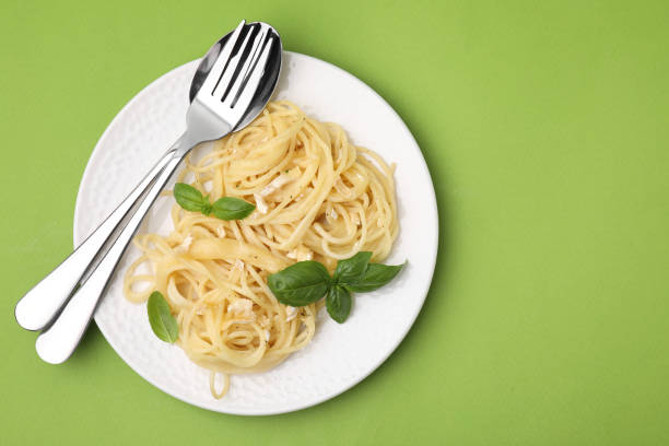 istock Delicious pasta with brie cheese and basil leaves on light green background, top view. Space for text 1870400941
