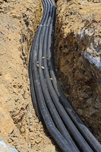 Black PVC corrugated conduit pipes in trench.