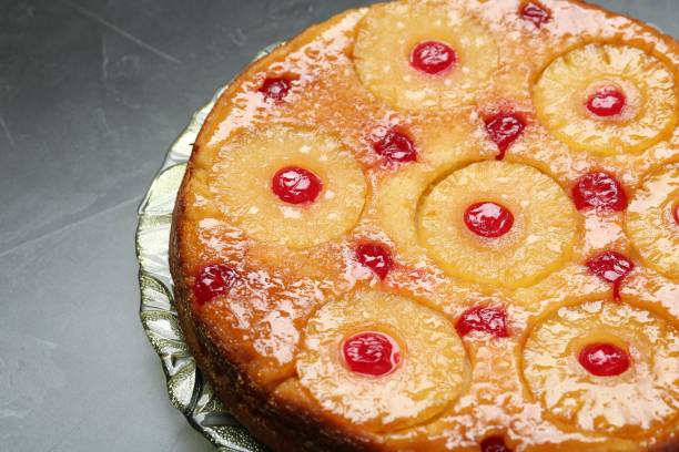 istock Plate with tasty pineapple cake on grey textured table, closeup. Space for text 1870418036
