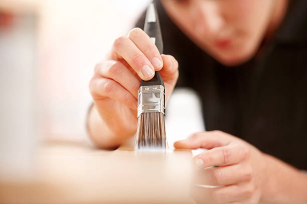istock Female carpenter applying varnish on wooden plank 187041867