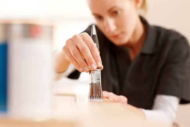 istock Female carpenter applying varnish on wooden plank 187041878