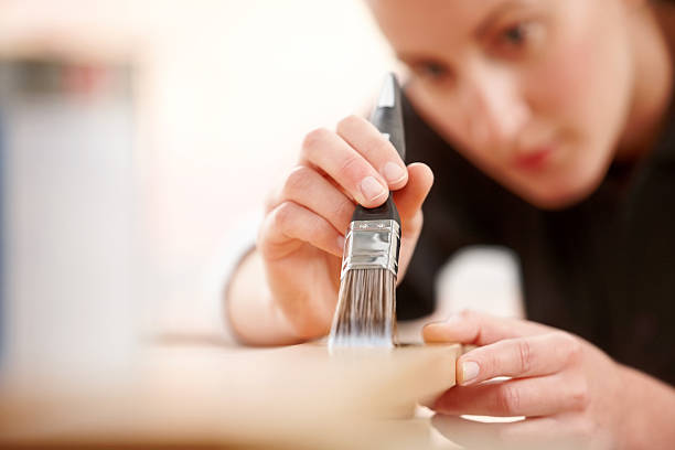 Female carpenter applying wood stain